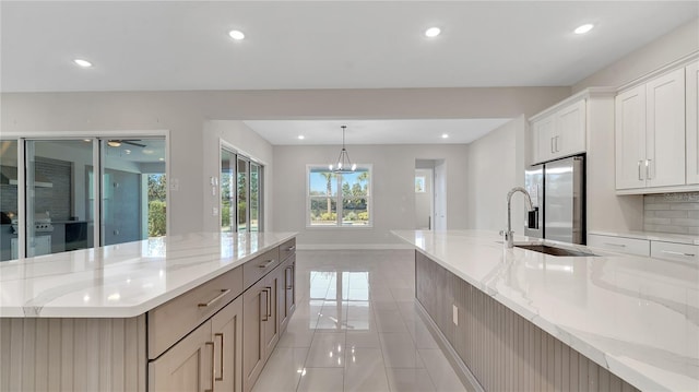 kitchen with recessed lighting, stainless steel fridge with ice dispenser, light stone countertops, and light tile patterned flooring