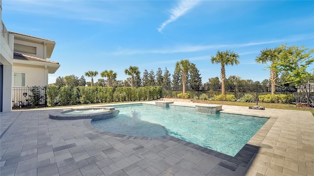 view of pool featuring a patio area, fence, and a pool with connected hot tub