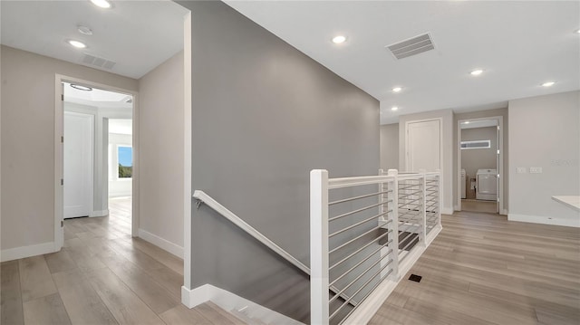 hall with an upstairs landing, visible vents, and independent washer and dryer