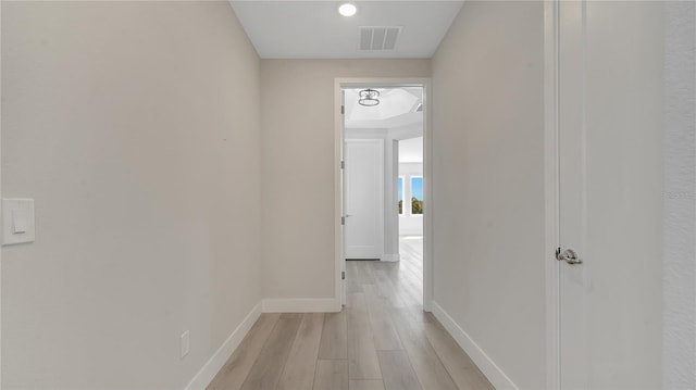 hall featuring visible vents, baseboards, and light wood-style flooring