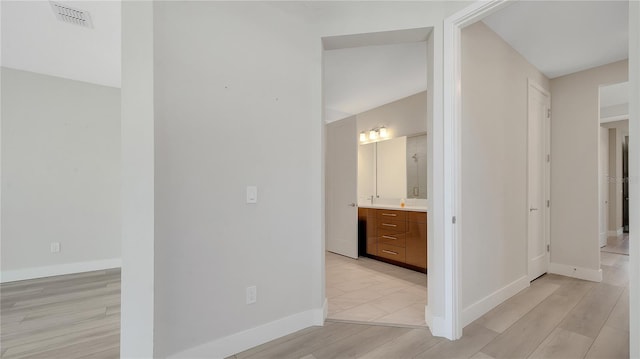 corridor featuring light wood-type flooring, baseboards, and visible vents