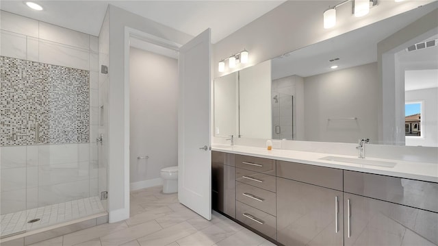 bathroom featuring visible vents, toilet, a sink, a shower stall, and double vanity