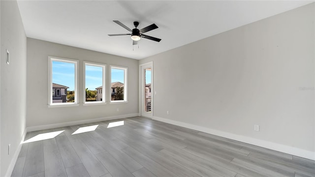 empty room featuring baseboards, wood finished floors, and ceiling fan