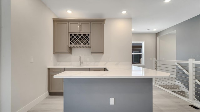 kitchen featuring baseboards, recessed lighting, a sink, gray cabinetry, and light countertops