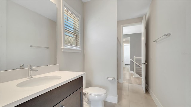 bathroom with tile patterned flooring, toilet, vanity, and baseboards