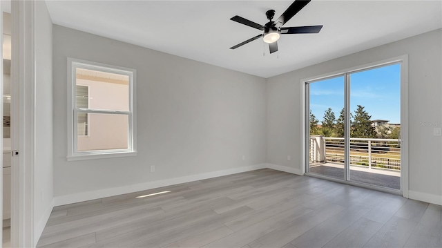 spare room with baseboards, light wood-style flooring, and a ceiling fan