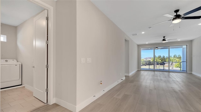 interior space featuring a ceiling fan, visible vents, baseboards, light wood-style flooring, and washer / clothes dryer