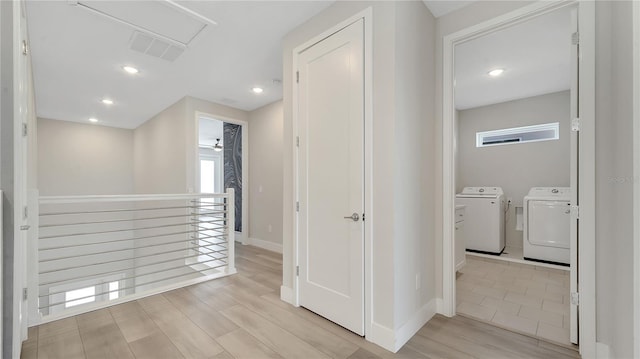 hall featuring an upstairs landing, visible vents, washer and dryer, and light wood-style flooring