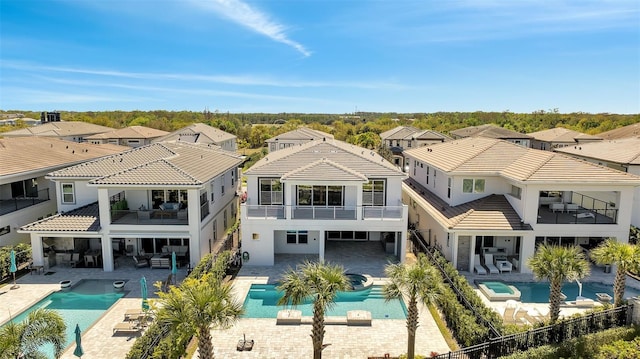 rear view of house featuring a tile roof, a balcony, a patio area, and stucco siding