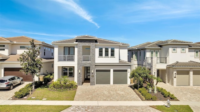 view of front of home with a balcony, decorative driveway, a garage, and stucco siding