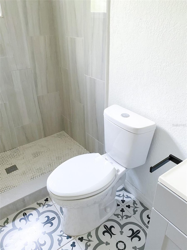 bathroom featuring a textured wall, tile patterned flooring, toilet, baseboards, and a stall shower