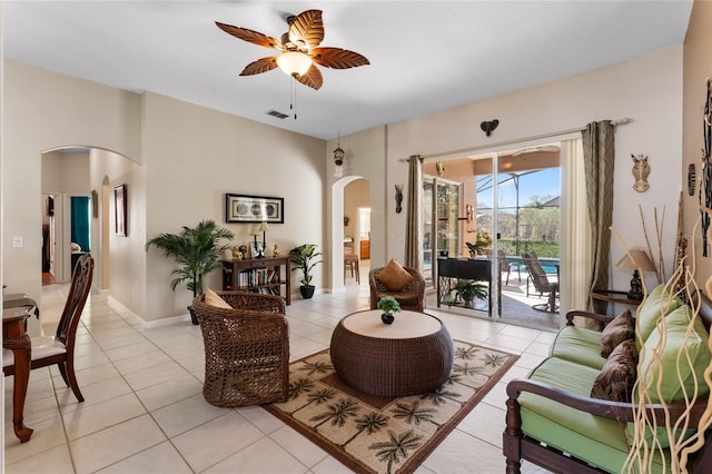 living area featuring arched walkways, ceiling fan, light tile patterned floors, visible vents, and baseboards