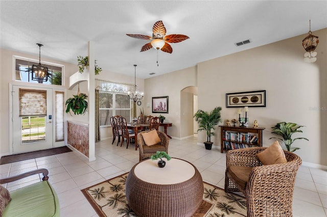 living room featuring visible vents, arched walkways, baseboards, light tile patterned flooring, and ceiling fan with notable chandelier