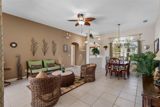 living area featuring arched walkways, light tile patterned floors, ceiling fan with notable chandelier, visible vents, and baseboards