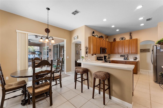 kitchen with arched walkways, stainless steel appliances, visible vents, light countertops, and decorative light fixtures