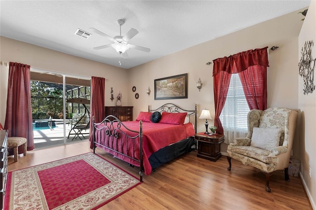 bedroom featuring a textured ceiling, multiple windows, wood finished floors, and access to exterior