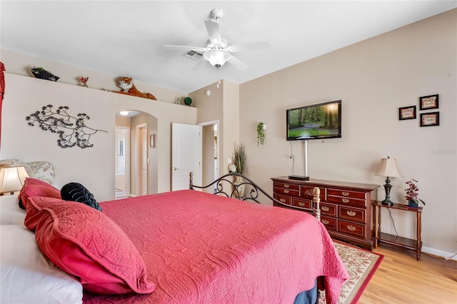 bedroom featuring light wood finished floors, visible vents, arched walkways, and a ceiling fan