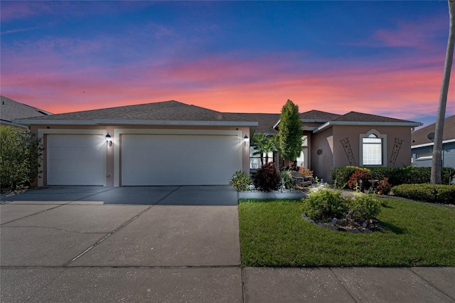 ranch-style house featuring a garage, driveway, roof with shingles, stucco siding, and a front yard