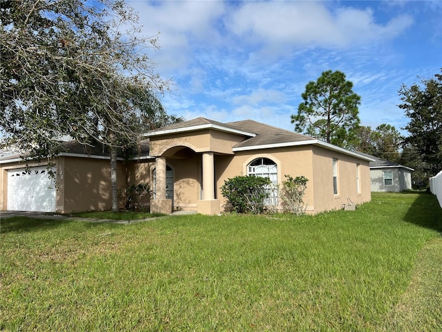 view of front of home with a front yard, an attached garage, and stucco siding