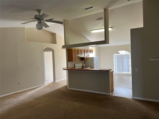 kitchen featuring visible vents, light carpet, a ceiling fan, arched walkways, and lofted ceiling