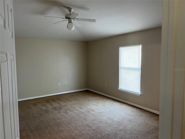 carpeted spare room with baseboards and a ceiling fan