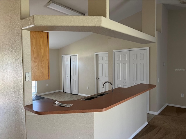 kitchen with vaulted ceiling, baseboards, and a sink