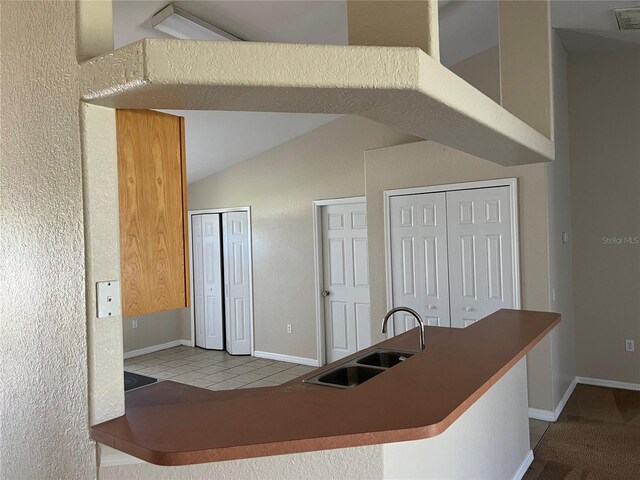 kitchen with tile patterned flooring, visible vents, baseboards, vaulted ceiling, and a sink