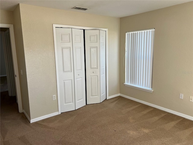 unfurnished bedroom featuring visible vents, baseboards, carpet, and a closet