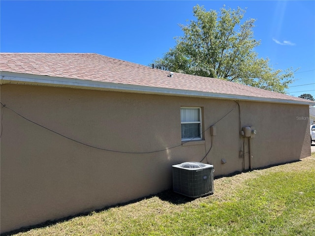 view of property exterior featuring a yard, central AC unit, stucco siding, and a shingled roof