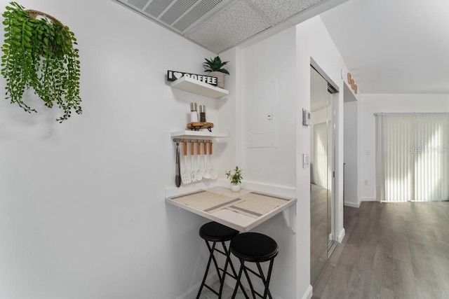 hall with a drop ceiling, baseboards, and wood finished floors