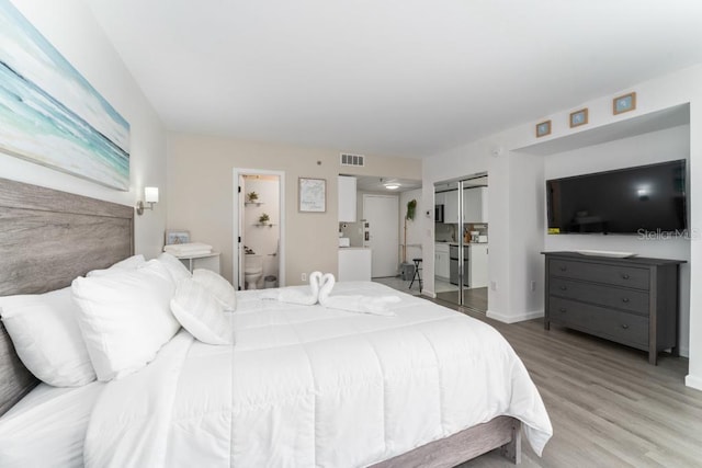 bedroom with baseboards, connected bathroom, visible vents, and light wood-style floors