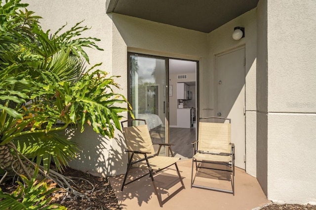 doorway to property featuring visible vents and stucco siding