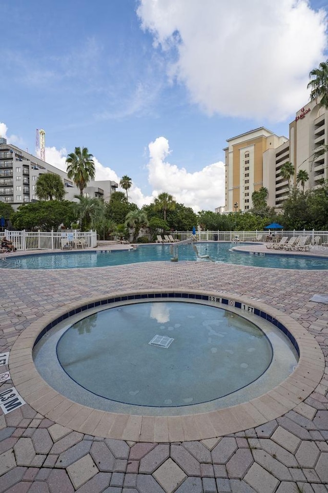 view of pool with a community hot tub and fence