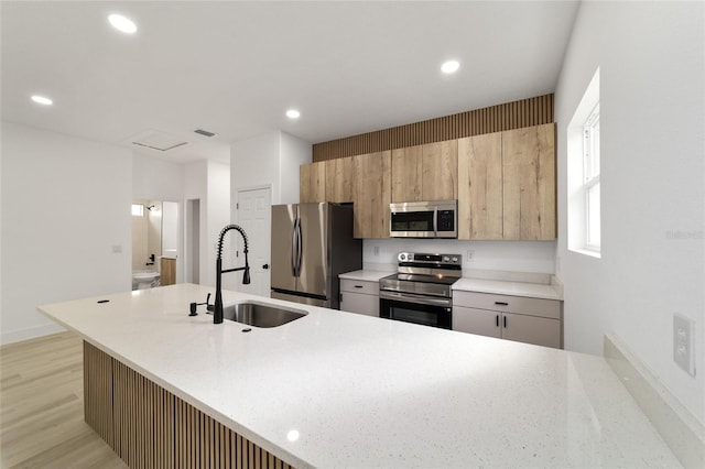 kitchen with a sink, recessed lighting, light wood finished floors, and stainless steel appliances