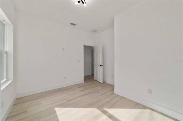 unfurnished room with light wood-style flooring, baseboards, and visible vents