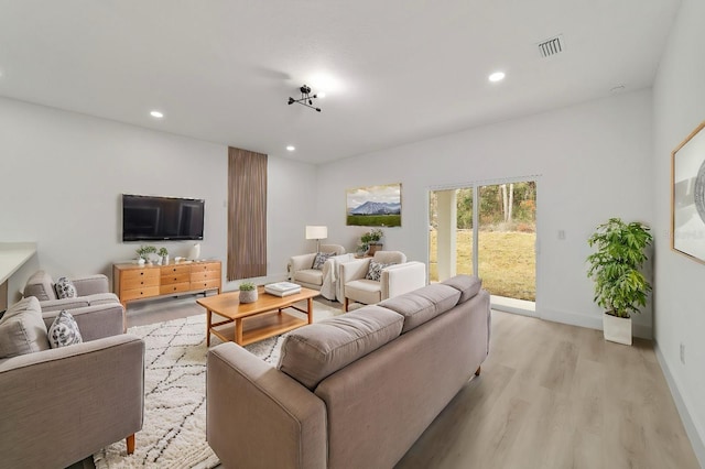 living room with light wood-type flooring, visible vents, baseboards, and recessed lighting