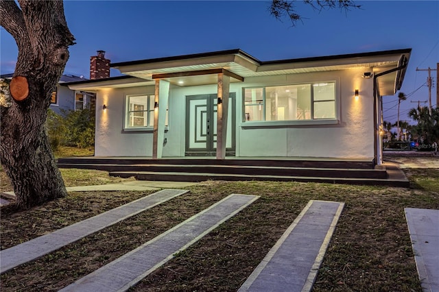 view of front of home featuring a chimney and stucco siding