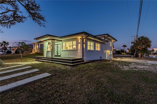 view of front of house featuring a front yard, covered porch, and stucco siding