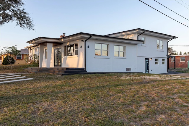 view of front of property with a chimney, a front yard, and stucco siding