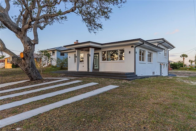 view of front of house featuring a chimney, a front yard, and stucco siding