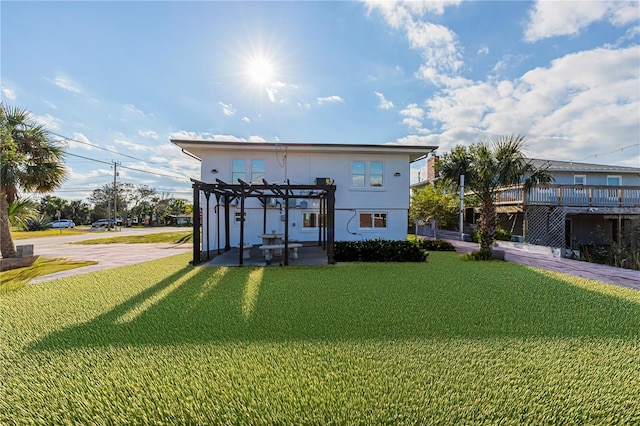 rear view of property featuring a lawn, stucco siding, and a pergola