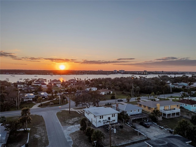 aerial view at dusk with a residential view and a water view