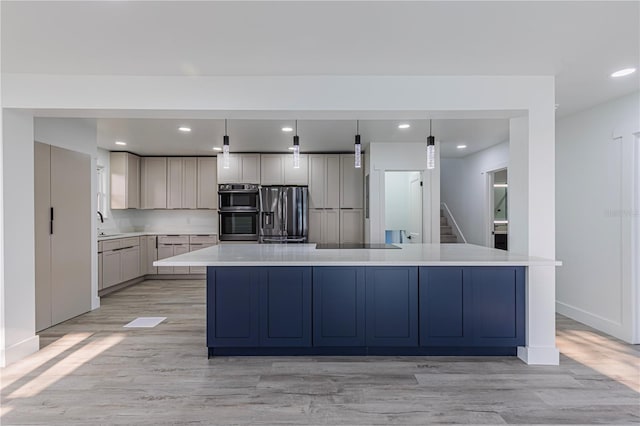 kitchen with appliances with stainless steel finishes, pendant lighting, light countertops, and a center island