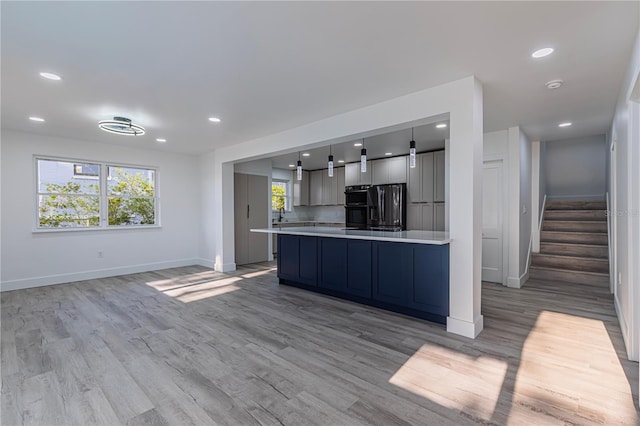 kitchen featuring light wood finished floors, baseboards, hanging light fixtures, light countertops, and refrigerator with ice dispenser