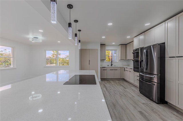 kitchen featuring a sink, white cabinetry, hanging light fixtures, light stone countertops, and black appliances