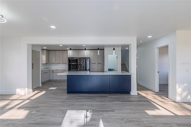 kitchen featuring a kitchen island, light countertops, gray cabinets, light wood finished floors, and stainless steel fridge