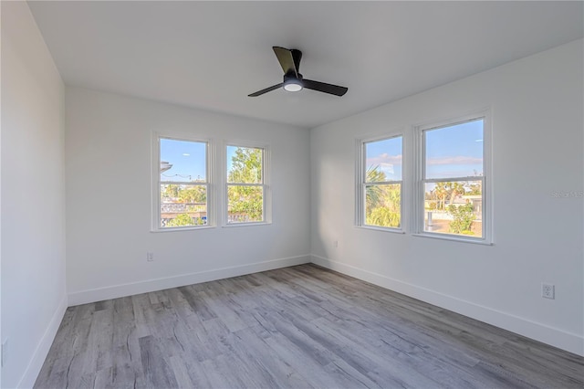 spare room featuring a ceiling fan, baseboards, and light wood finished floors