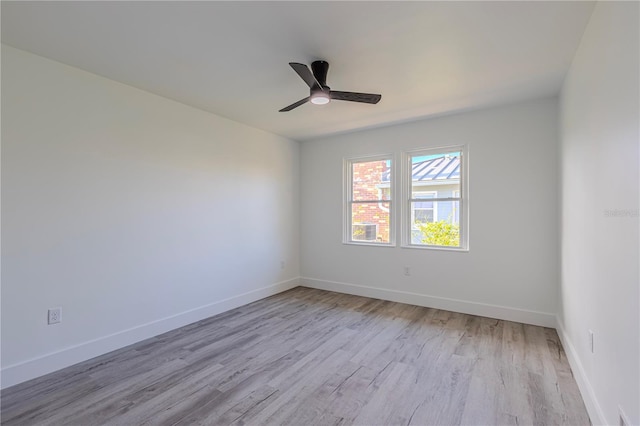 spare room featuring light wood-style floors, baseboards, and a ceiling fan