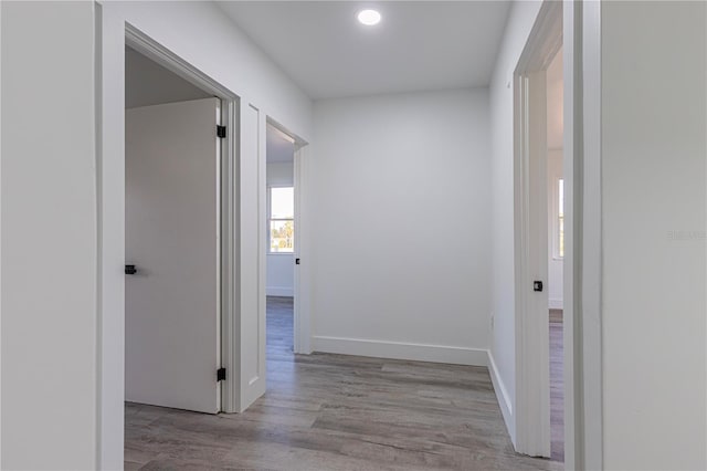 hall featuring light wood-style flooring and baseboards