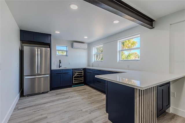 kitchen with light countertops, a wall mounted AC, freestanding refrigerator, beverage cooler, and a peninsula